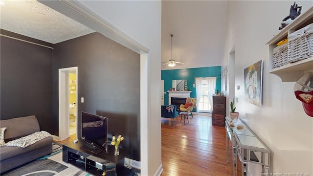 living room featuring ceiling fan, hardwood / wood-style floors, and a textured ceiling