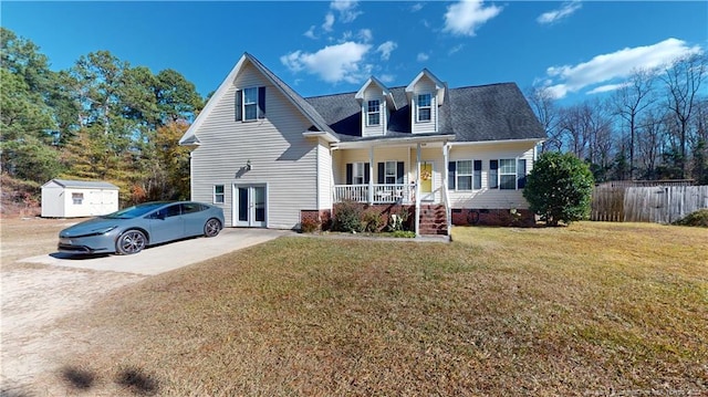 cape cod-style house featuring covered porch, a front yard, and a storage unit