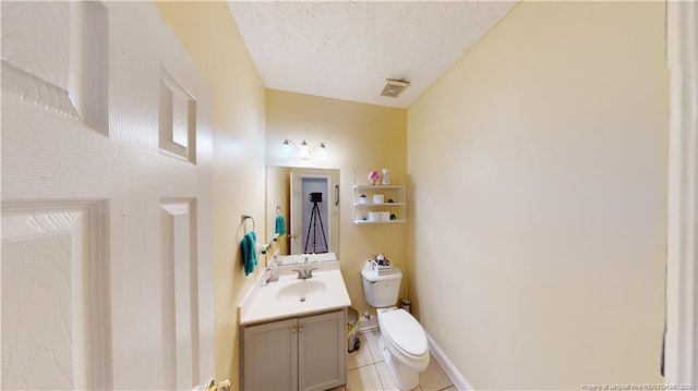 bathroom featuring tile patterned floors, vanity, a textured ceiling, and toilet