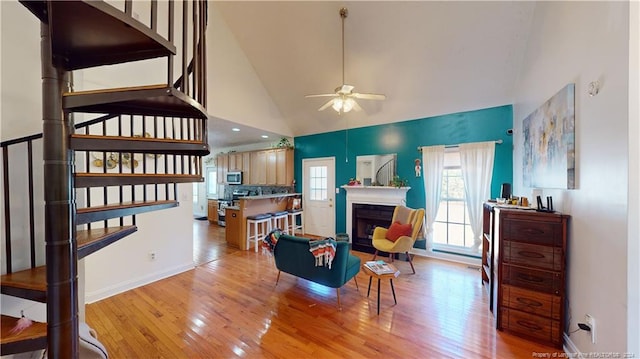 living room with ceiling fan, light hardwood / wood-style floors, and high vaulted ceiling