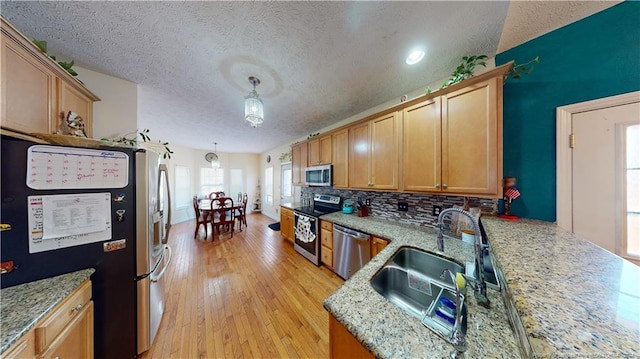 kitchen featuring pendant lighting, a textured ceiling, stainless steel appliances, and sink