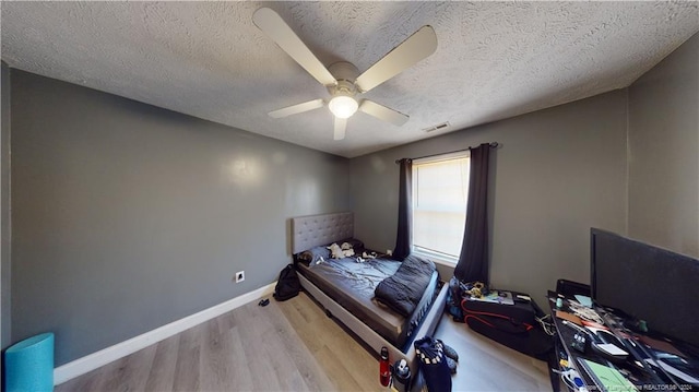 bedroom featuring ceiling fan, a textured ceiling, and light wood-type flooring