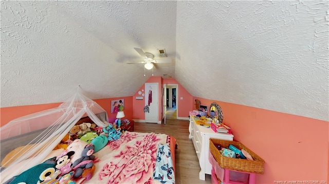 bedroom with a textured ceiling, hardwood / wood-style flooring, ceiling fan, and lofted ceiling