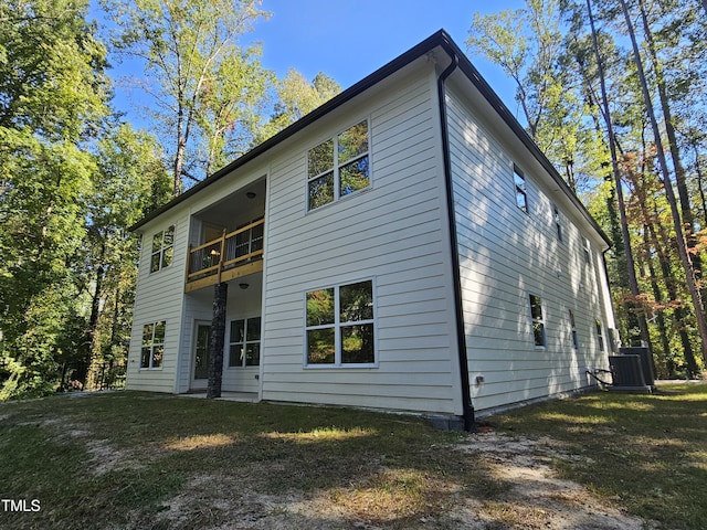 rear view of property featuring a yard, a balcony, and central AC unit