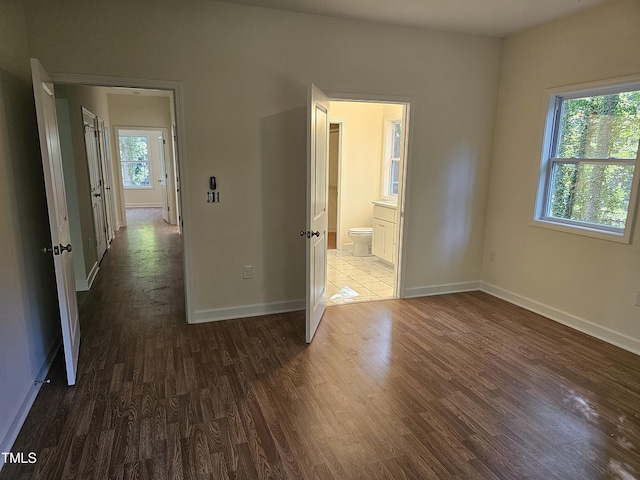 interior space with ensuite bath, multiple windows, and dark wood-type flooring