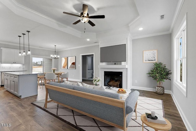 living room featuring hardwood / wood-style flooring, ceiling fan with notable chandelier, and ornamental molding