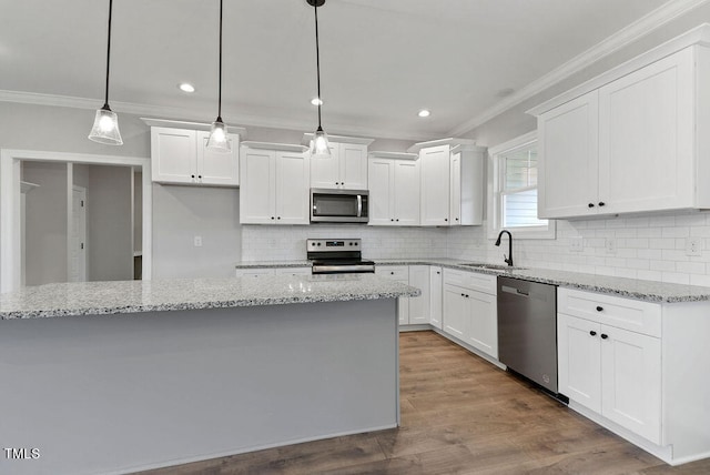 kitchen with pendant lighting, hardwood / wood-style floors, white cabinets, a kitchen island, and stainless steel appliances