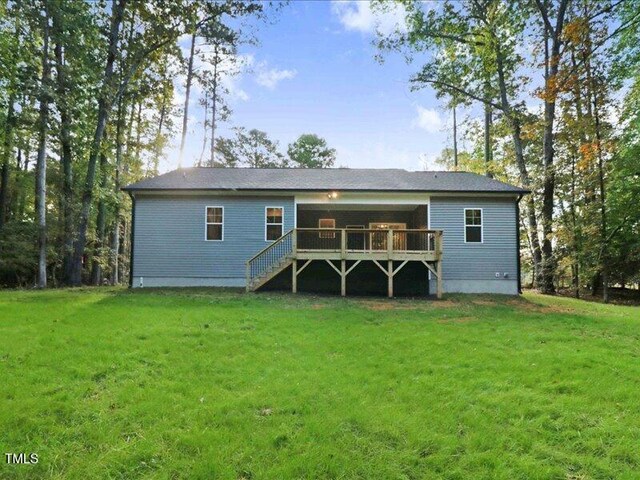 rear view of property featuring a lawn and a wooden deck