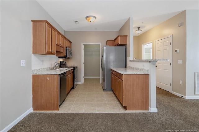 kitchen with light colored carpet, light stone countertops, sink, and appliances with stainless steel finishes