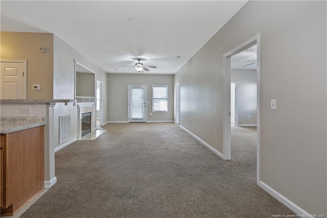 unfurnished living room featuring light carpet, ceiling fan, and a high end fireplace