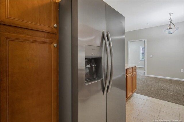 kitchen featuring light stone countertops, stainless steel fridge with ice dispenser, pendant lighting, and light colored carpet