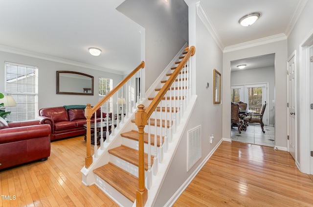 stairs featuring crown molding, french doors, and hardwood / wood-style flooring