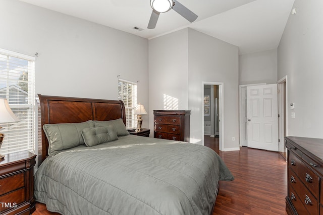 bedroom with ceiling fan, a towering ceiling, dark wood-type flooring, and multiple windows