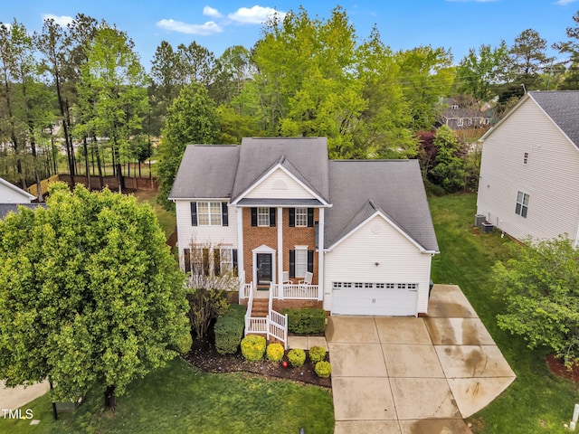 neoclassical / greek revival house featuring a front yard, driveway, a porch, and a garage