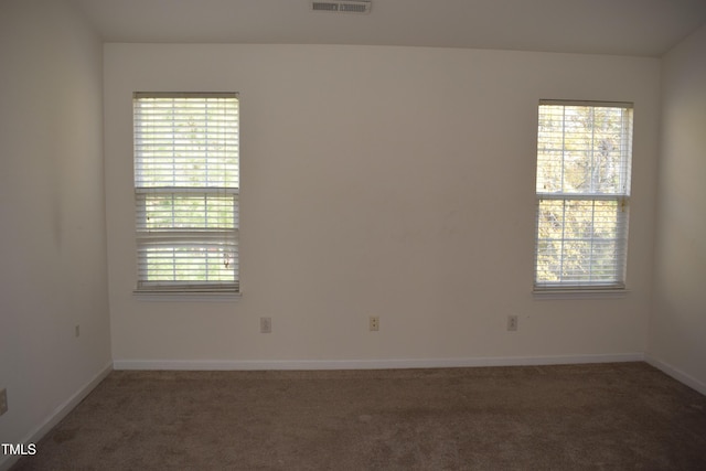 spare room with dark colored carpet and a healthy amount of sunlight