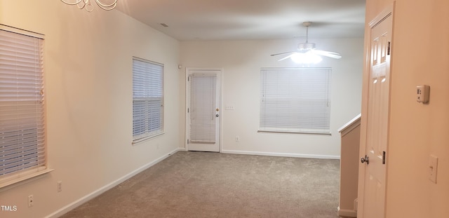 spare room featuring ceiling fan with notable chandelier and carpet floors