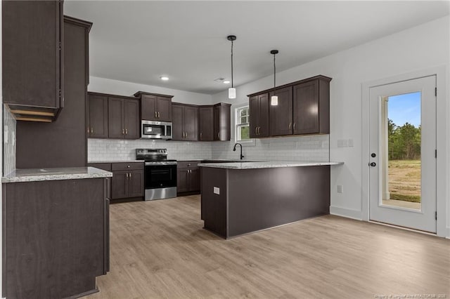 kitchen with appliances with stainless steel finishes, a peninsula, light wood-style flooring, and dark brown cabinetry