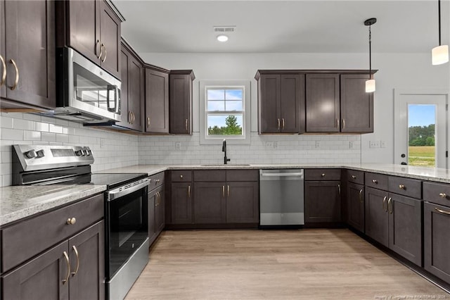 kitchen with dark brown cabinetry, a sink, appliances with stainless steel finishes, and a healthy amount of sunlight