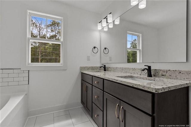 bathroom with a bath, double vanity, a sink, and baseboards