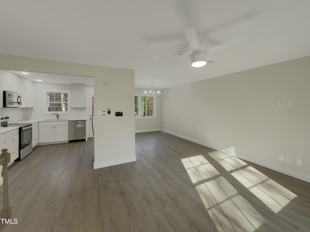 unfurnished living room with light hardwood / wood-style flooring, ceiling fan with notable chandelier, and sink