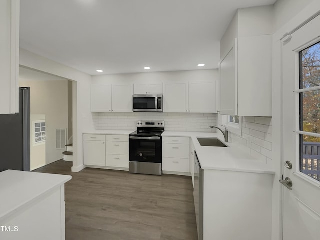 302 N Montreal Ct, Cary, NC 27511 - kitchen with stainless steel appliances, a sink, white cabinetry, backsplash, and light countertops