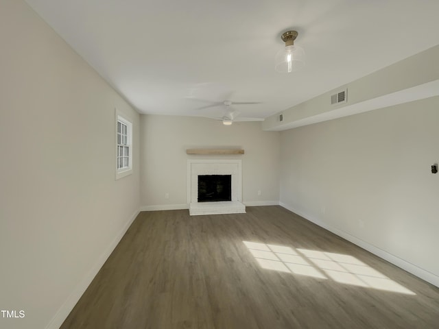 unfurnished living room featuring ceiling fan, hardwood / wood-style floors, and a brick fireplace