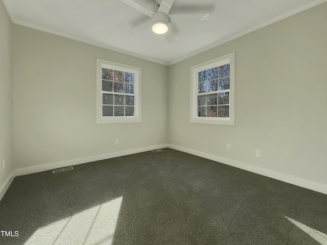 empty room featuring dark colored carpet, ceiling fan, crown molding, and a wealth of natural light