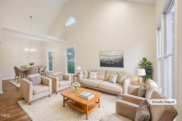 living room featuring dark hardwood / wood-style flooring, high vaulted ceiling, and an inviting chandelier