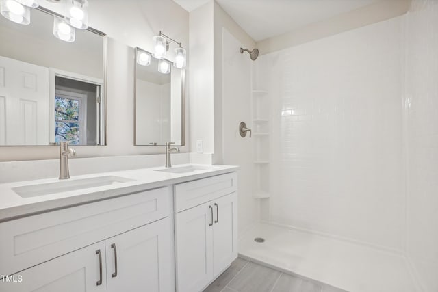 bathroom featuring tile patterned flooring, vanity, and tiled shower