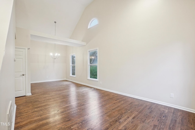 spare room featuring high vaulted ceiling, dark hardwood / wood-style floors, and an inviting chandelier