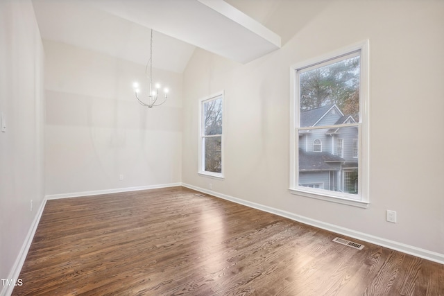 spare room featuring dark wood-type flooring, vaulted ceiling, and a notable chandelier