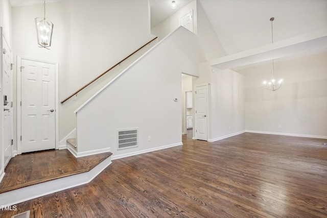 unfurnished living room with dark hardwood / wood-style flooring, high vaulted ceiling, and a chandelier