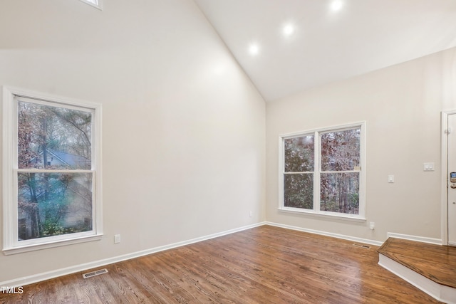 spare room featuring hardwood / wood-style flooring and high vaulted ceiling