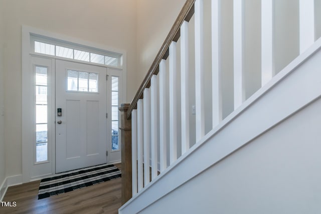 foyer entrance with stairs, a wealth of natural light, a high ceiling, and wood finished floors