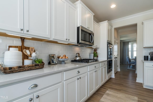 kitchen featuring white cabinetry, light countertops, appliances with stainless steel finishes, light wood-type flooring, and backsplash