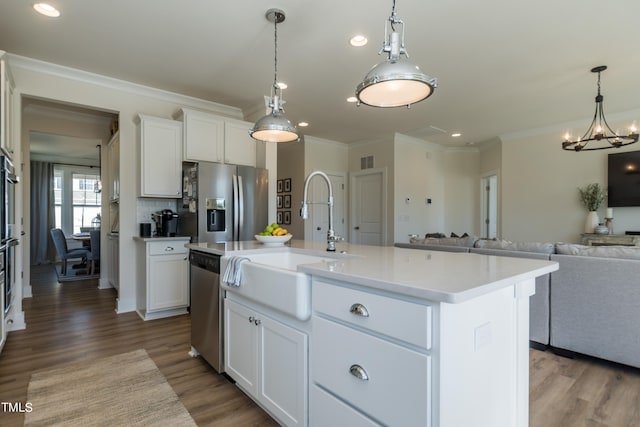 kitchen featuring white cabinets, open floor plan, wood finished floors, stainless steel appliances, and a sink