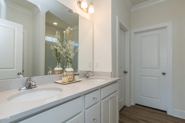 bathroom with crown molding, visible vents, a sink, and wood finished floors