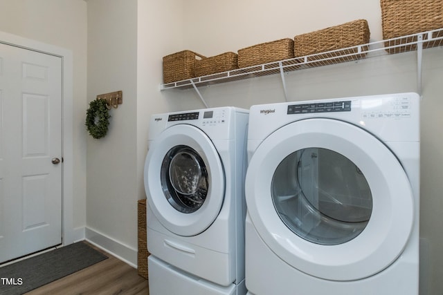 clothes washing area featuring washing machine and dryer, laundry area, baseboards, and wood finished floors