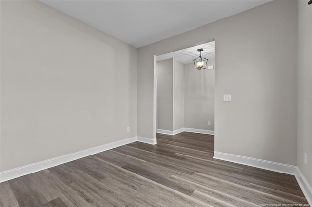 unfurnished room featuring dark wood-type flooring and a chandelier