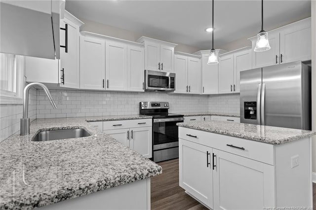 kitchen with appliances with stainless steel finishes, pendant lighting, white cabinetry, sink, and light stone countertops