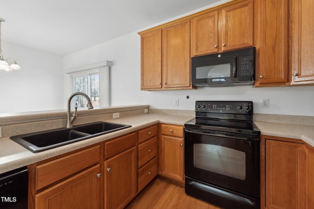 kitchen with sink, decorative light fixtures, a chandelier, light wood-type flooring, and black appliances