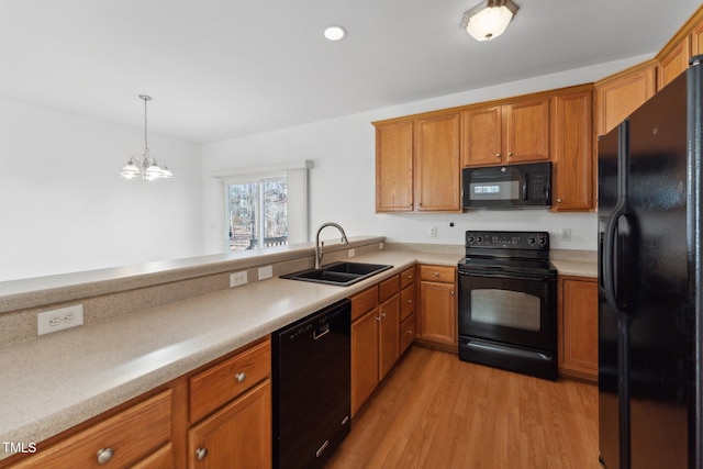 kitchen featuring pendant lighting, sink, black appliances, and light hardwood / wood-style floors