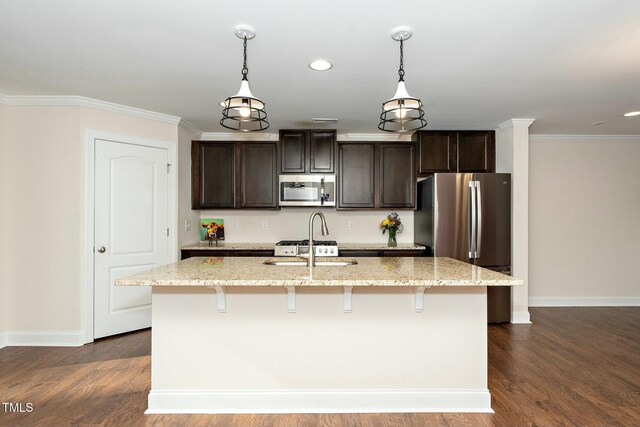 kitchen featuring stainless steel appliances, light stone counters, a kitchen island with sink, and dark wood-type flooring