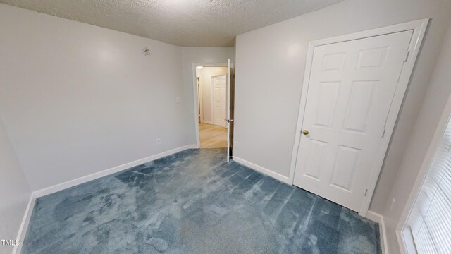 unfurnished bedroom featuring dark colored carpet and a textured ceiling