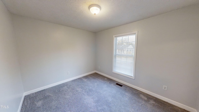 carpeted empty room featuring a textured ceiling