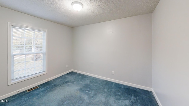 unfurnished room with dark colored carpet and a textured ceiling