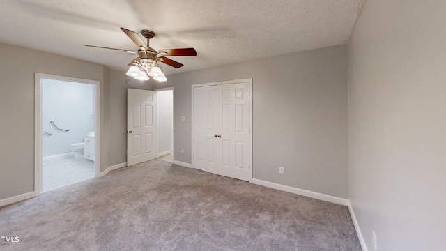 unfurnished bedroom with light carpet, ceiling fan, a textured ceiling, connected bathroom, and a closet