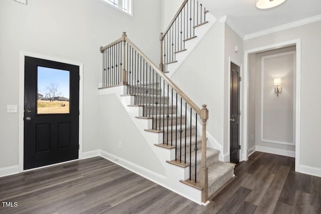 entryway featuring dark hardwood / wood-style flooring, crown molding, and a high ceiling