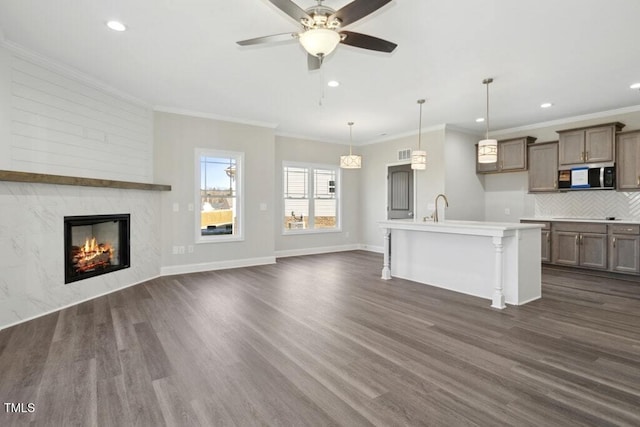 unfurnished living room featuring crown molding, a high end fireplace, dark hardwood / wood-style flooring, and sink