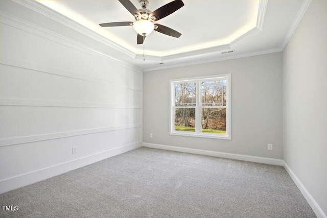 carpeted spare room with crown molding, ceiling fan, and a raised ceiling